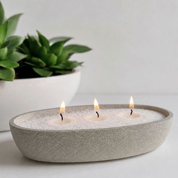 Velas decorativas encendidas en un recipiente de piedra.