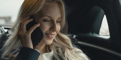 A woman smiling while talking on the phone in a car.