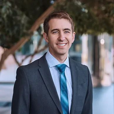 Young professional man in a suit smiling outdoors.