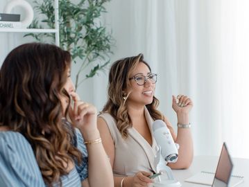 Two women engaged in a podcast recording.
