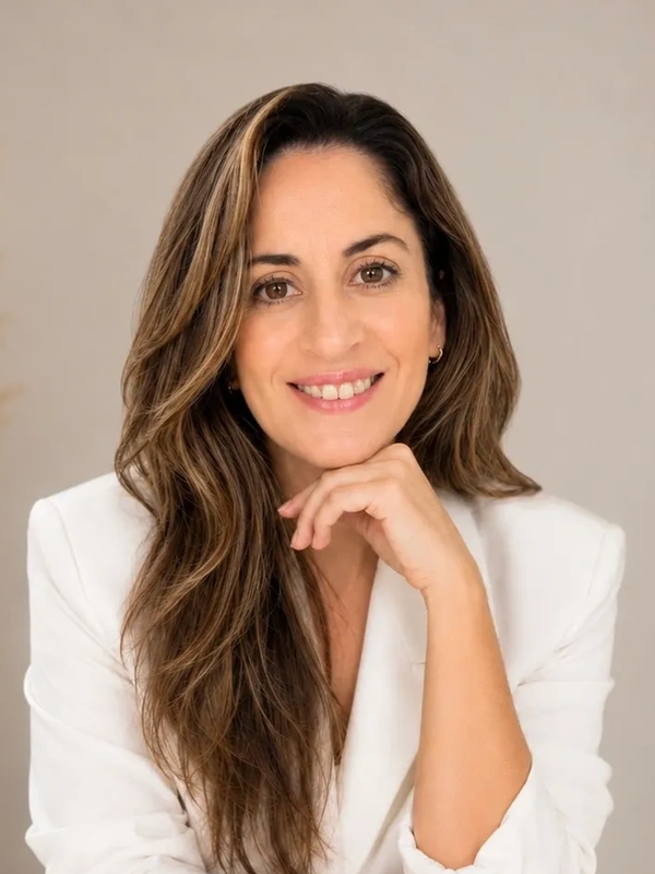 Mujer sonriente con cabello largo y chaqueta blanca.