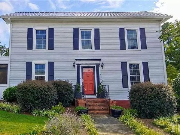White two-story house with blue shutters and a red front door.