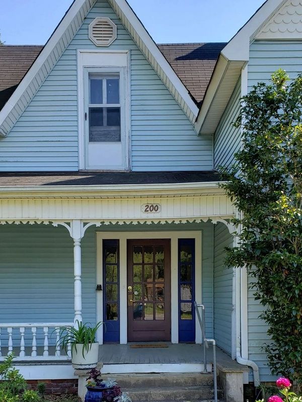 Front view of a charming blue house with a porch and decorative trim.