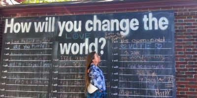 Chalkboard on a brick wall with writing on it. Beautiful girl standing in profile. 