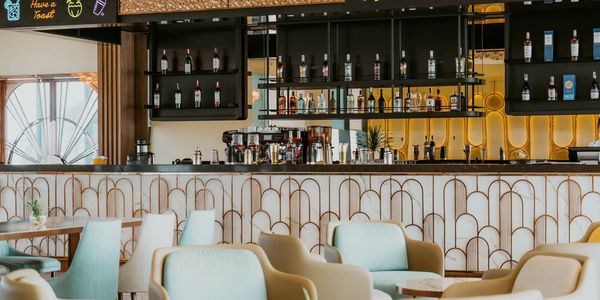 Stylish bar interior with pastel chairs and a decorative counter.