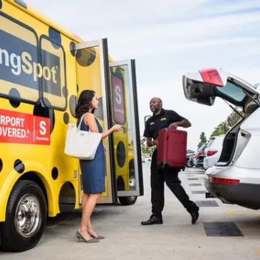 Driver helping woman load luggage from shuttle bus to car.