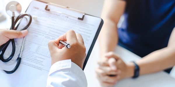 Photo of doctor with a clipboard talking to a patient