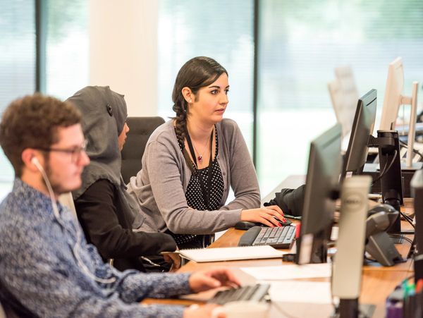 Three diverse coworkers focused on their computers in a modern office.