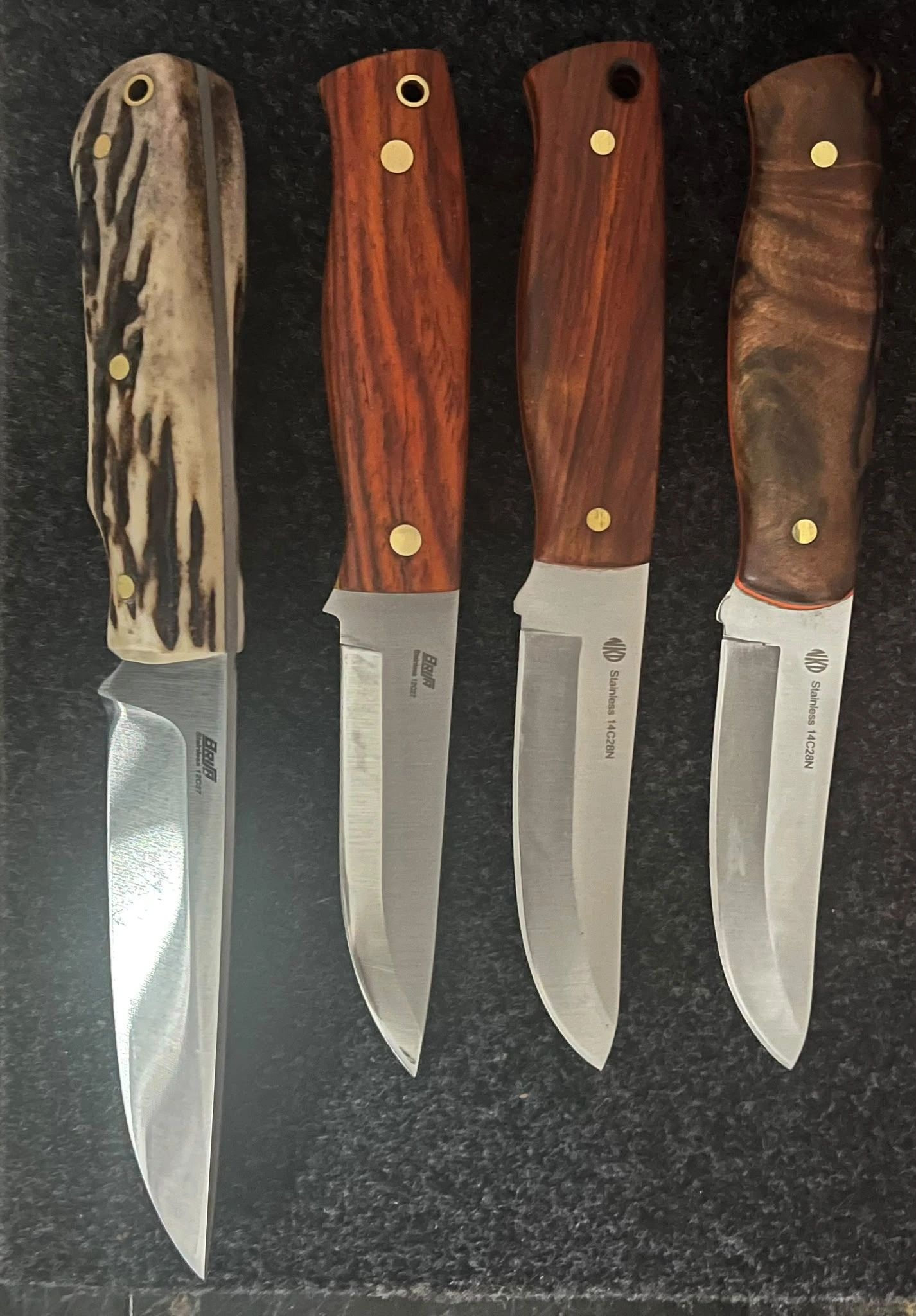 Four fixed-blade knives with different wooden handles.