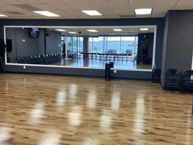 Empty dance studio with wooden floor and large mirror.