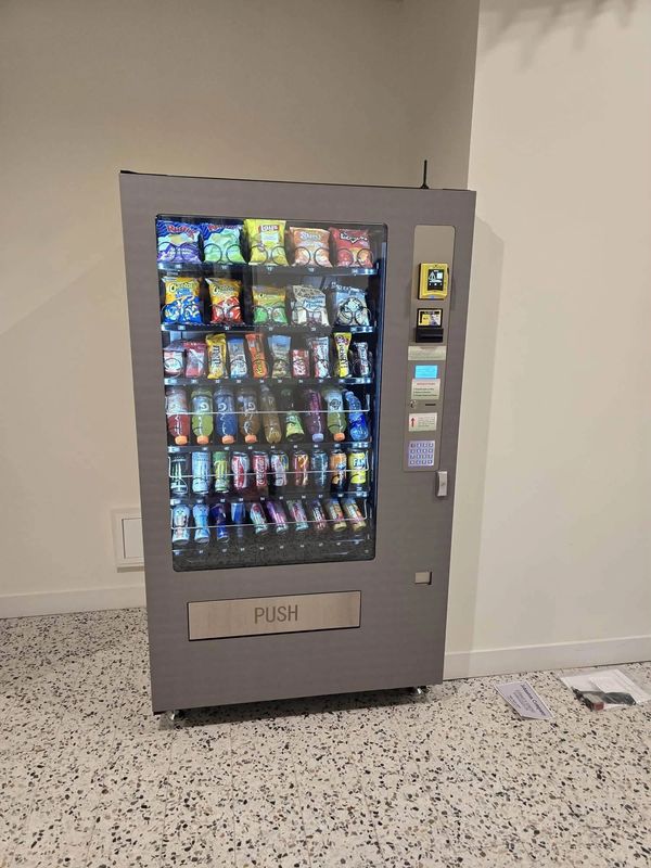 Snack and drink vending machine against a plain wall.