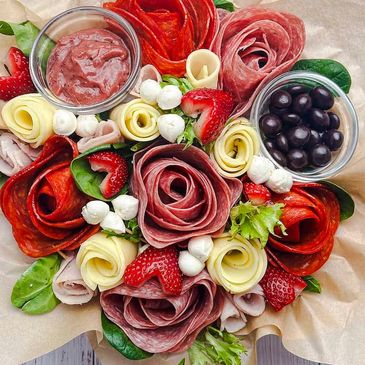 Charcuterie bouquet with meats, cheeses, strawberries, and olives.