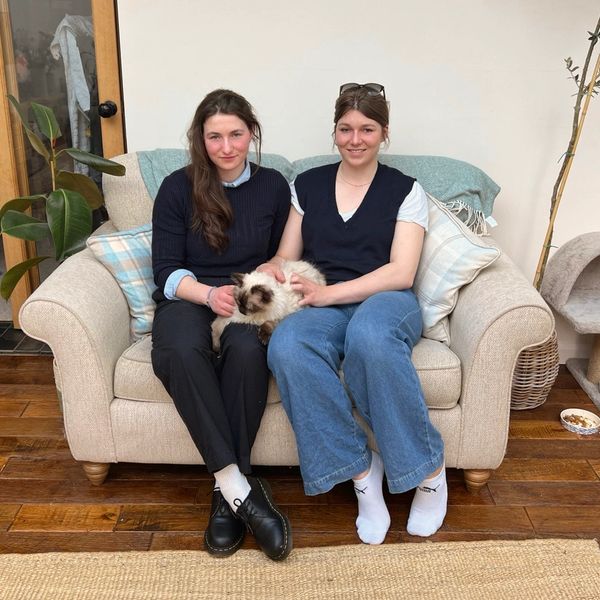 Two women sitting on a couch with a cat