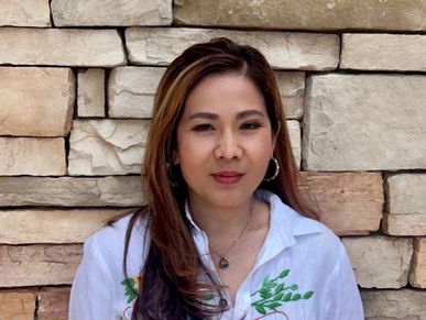 Woman in white shirt standing against a stone wall.