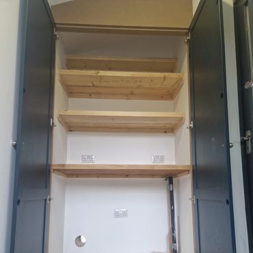 Empty closet with wooden shelves and electrical outlets inside.