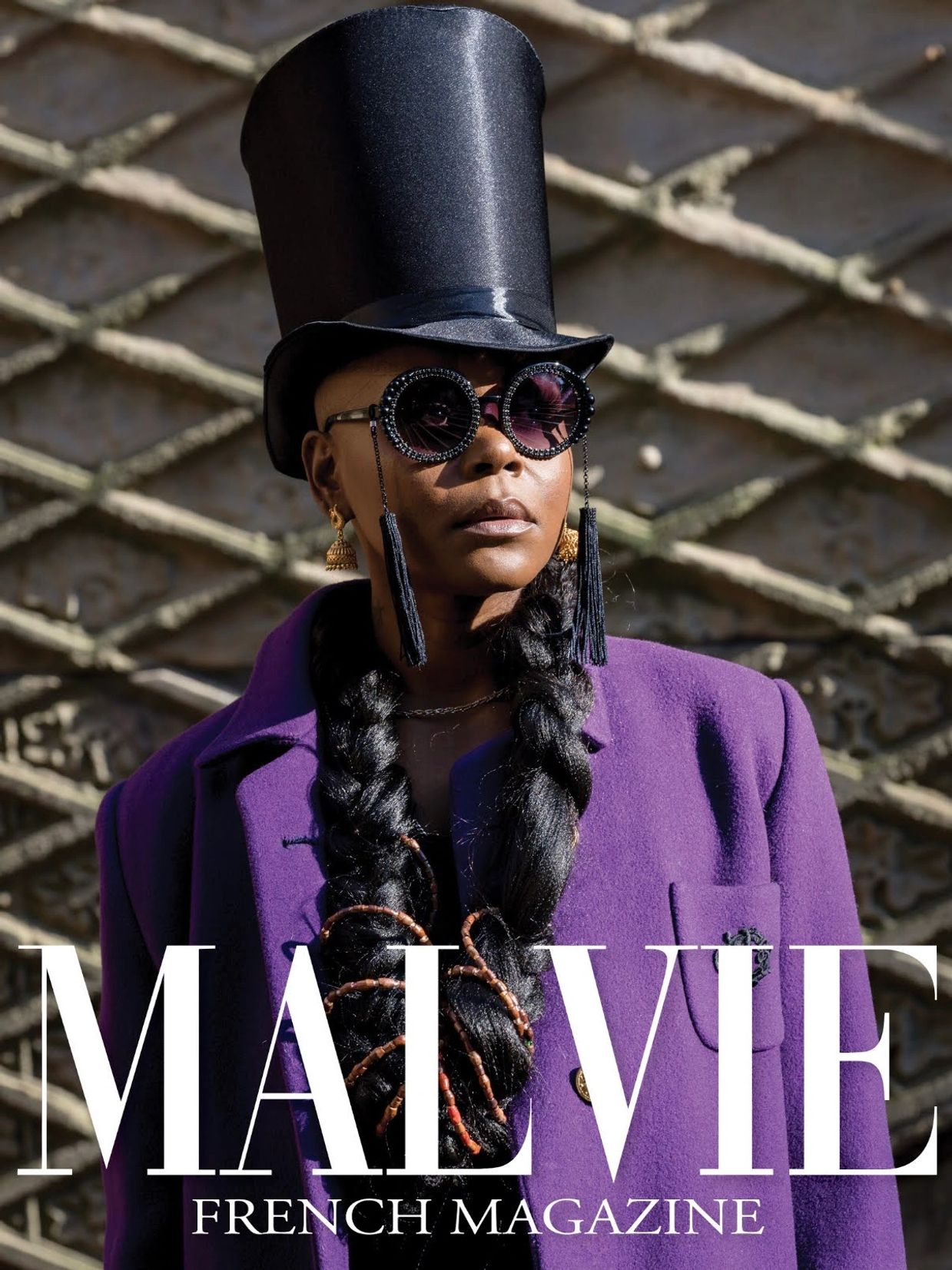 Fashion-forward individual in a tall black hat and purple coat on a magazine cover.