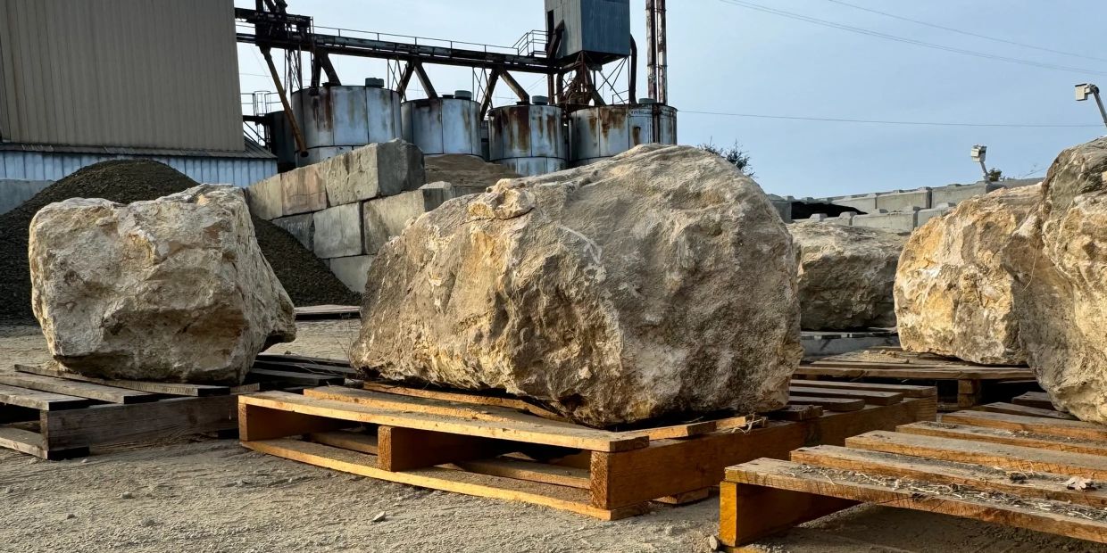 Large rocks placed on wooden pallets in an industrial area.