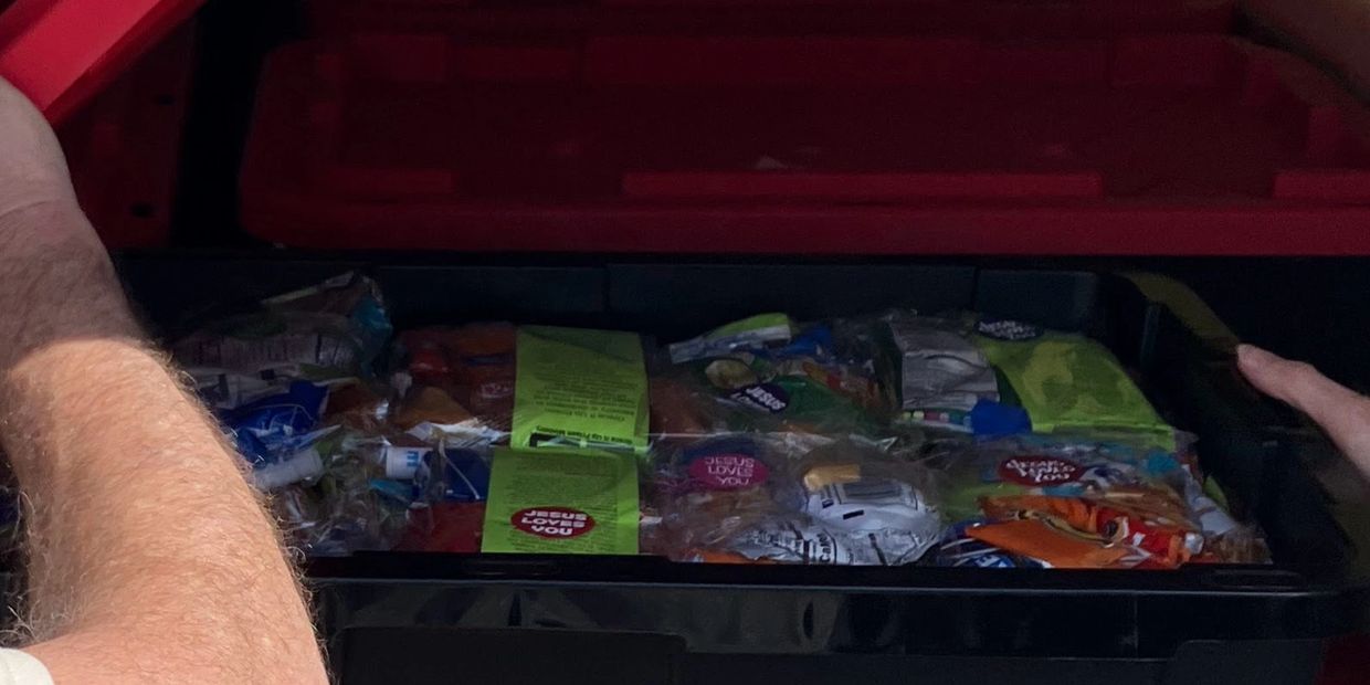 A storage bin filled with various packaged snacks and food items.