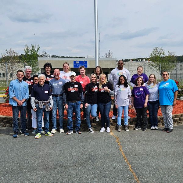 Group of people standing outdoors in front of a fenced area.