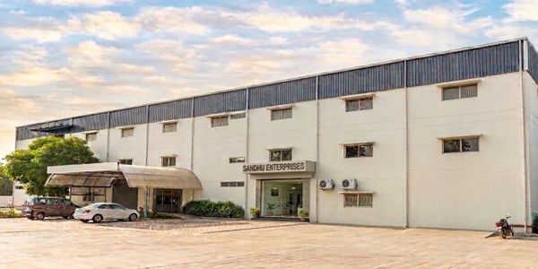 Exterior view of Sandhu Enterprises building with parked vehicles.