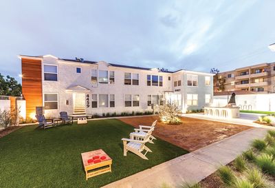 Modern apartment complex with outdoor seating and game area at dusk.