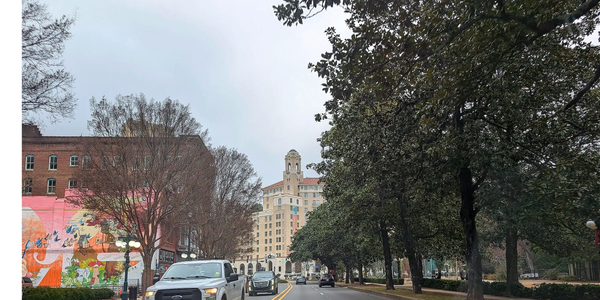 Street view with cars, trees, and a tall building in Hot Springs Arkansas