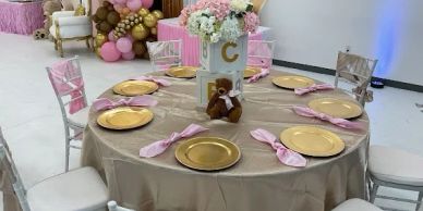 Round table with gold plates and pink napkins.