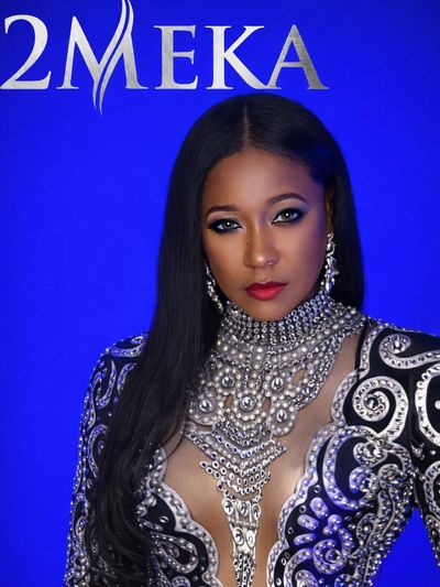 Confident woman in ornate black and silver dress against blue background.
