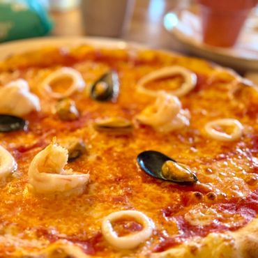 Close-up of a seafood pizza with shrimp, mussels, and calamari rings.