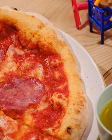 Close-up of a pepperoni pizza slice on a white plate with a green cup nearby.