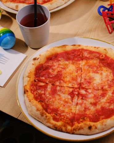 A classic cheese pizza with a drink on a wooden table.