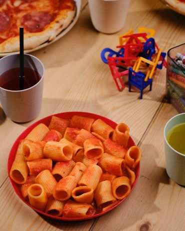 Plate of rigatoni pasta with tomato sauce on a wooden table.
