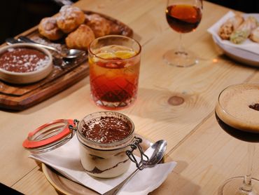 A dessert in a jar, drinks, and pastries on a wooden table.