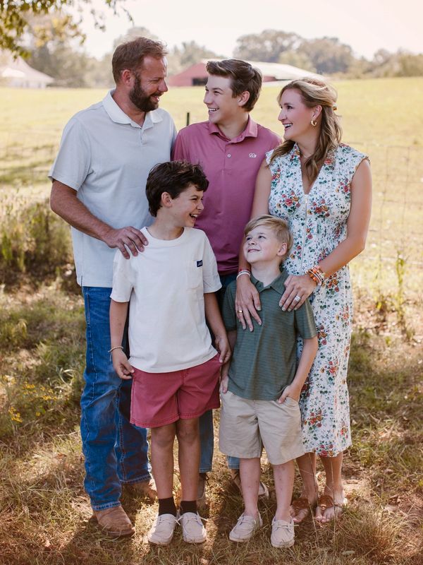 Smiling family of five outdoors in a sunny field.
