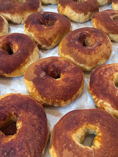 Freshly baked cinnamon-coated bagels on a tray.