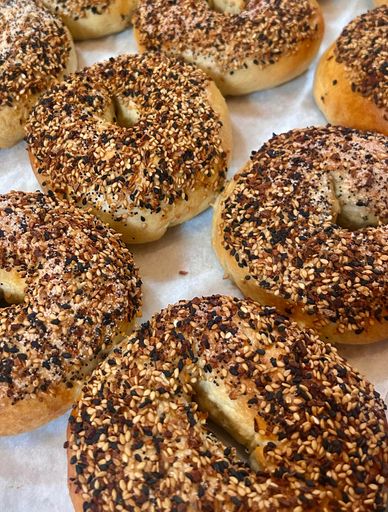 Freshly baked everything bagels covered with sesame seeds and seasoning.