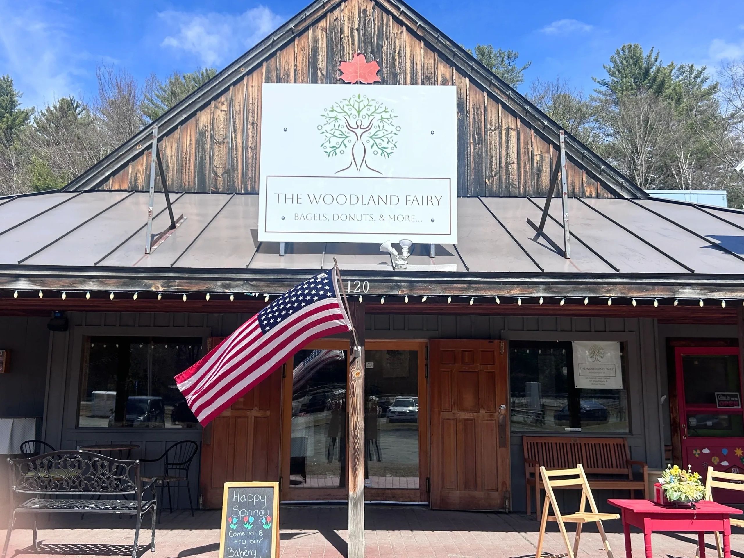 Front view of The Woodland Fairy bakery with American flag and spring sign.