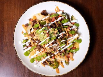 Plate of loaded nachos with various toppings.
