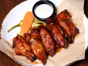 Glazed chicken wings with dipping sauce and vegetables.