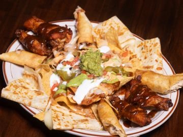 Plate of nachos with chicken wings and dips.