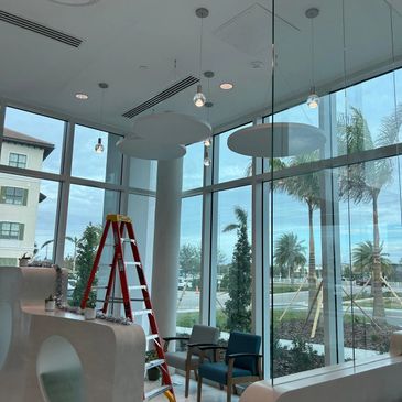 Modern indoor space with large windows, a red ladder, and hanging lights.