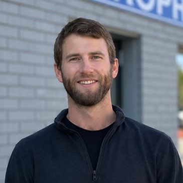 Smiling young man with beard outdoors.