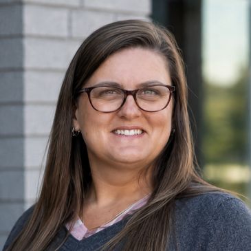 Smiling woman with glasses outdoors.