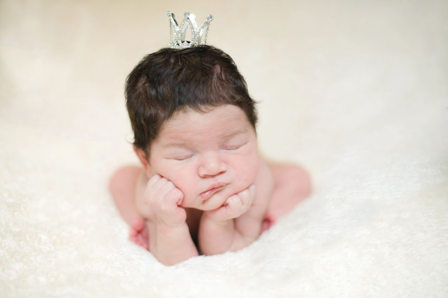 Newborn in frog position with a mini crown on her head. Newborn photo by Amber Whitaker Photography
