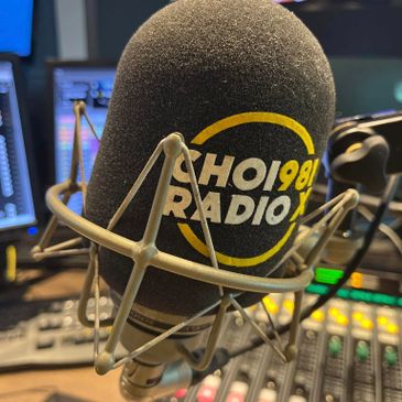 Close-up of a radio microphone with CHOI 98.1 FM logo in a studio.