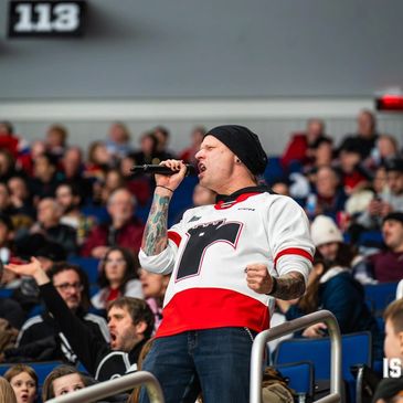 Man passionately singing into a microphone at a crowded sports event.
