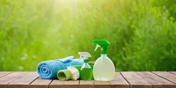 Cleaning supplies with towels and brushes on wooden table outdoors.