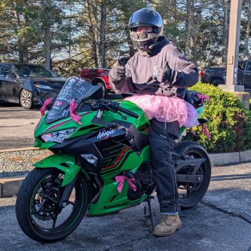 Person in a helmet and tutu on a green motorcycle.