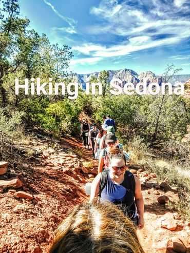 Group hiking on a scenic trail in Sedona with a beautiful sky.
