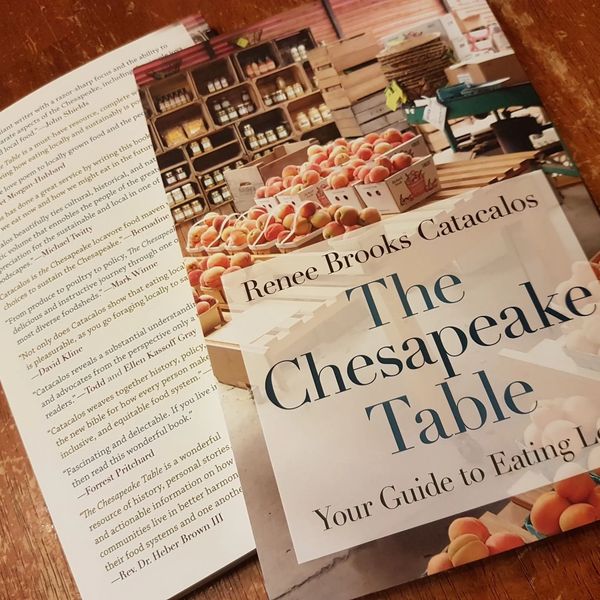 A book titled 'The Chesapeake Table' by Renee Brooks Catacalos with a cover image of fresh peaches at a market.